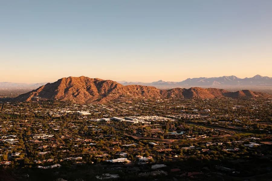 Aerial view of the Phoenix metro area at dusk with desert mountains on the horizon