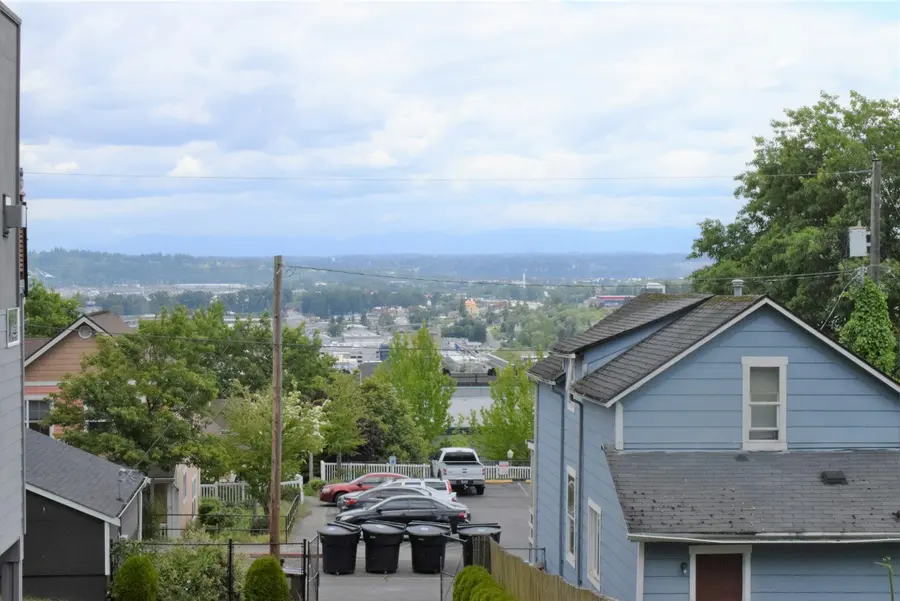 Residential street in Tacoma, Washington, with houses, trees and water in the distance