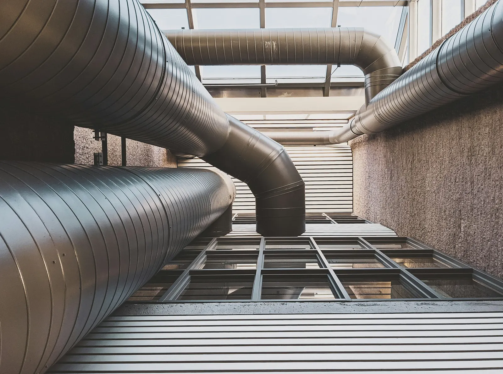 Large insulated ventilation ducts running along a building courtyard