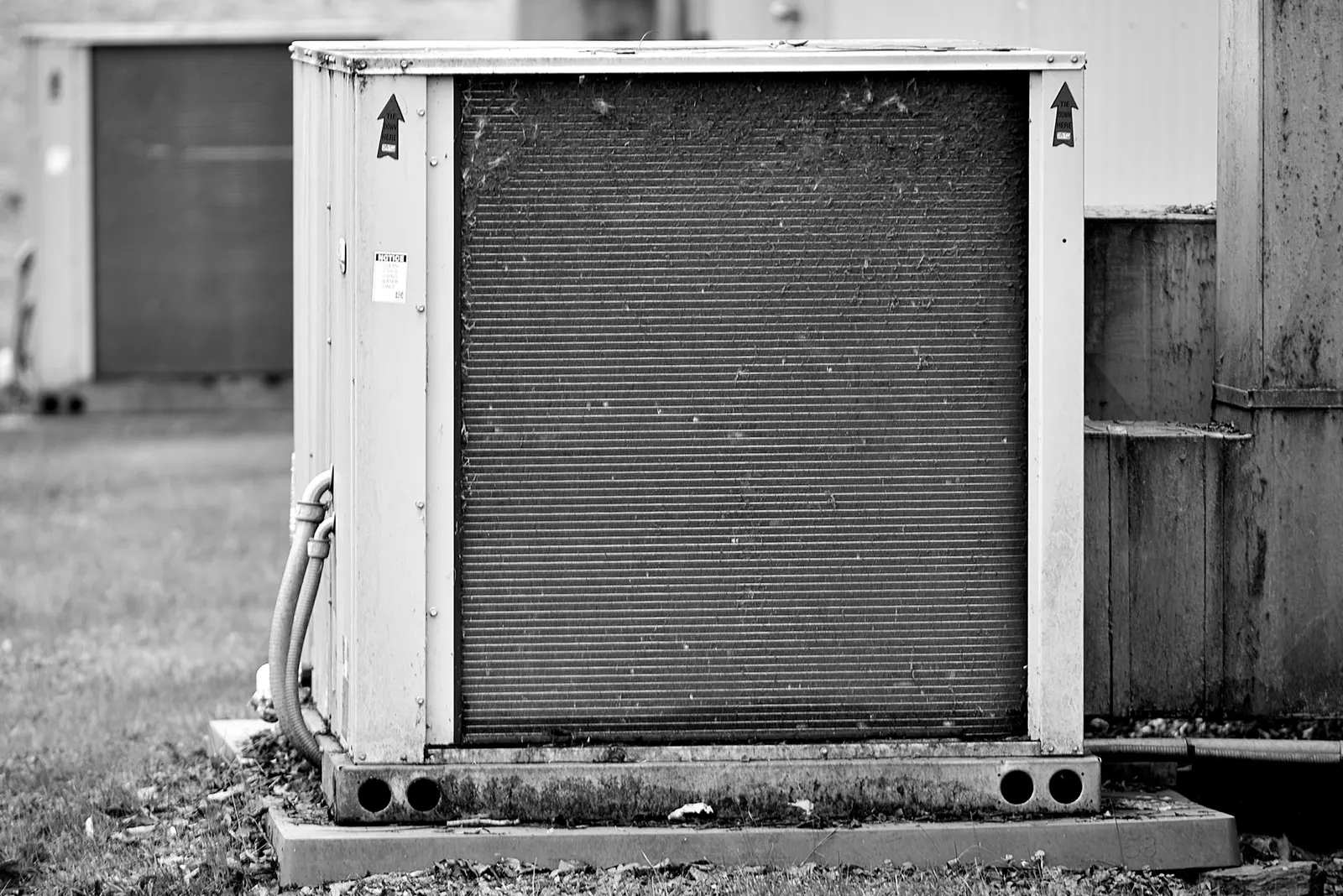 Weathered outdoor condensing unit with a dusty coil, in black and white