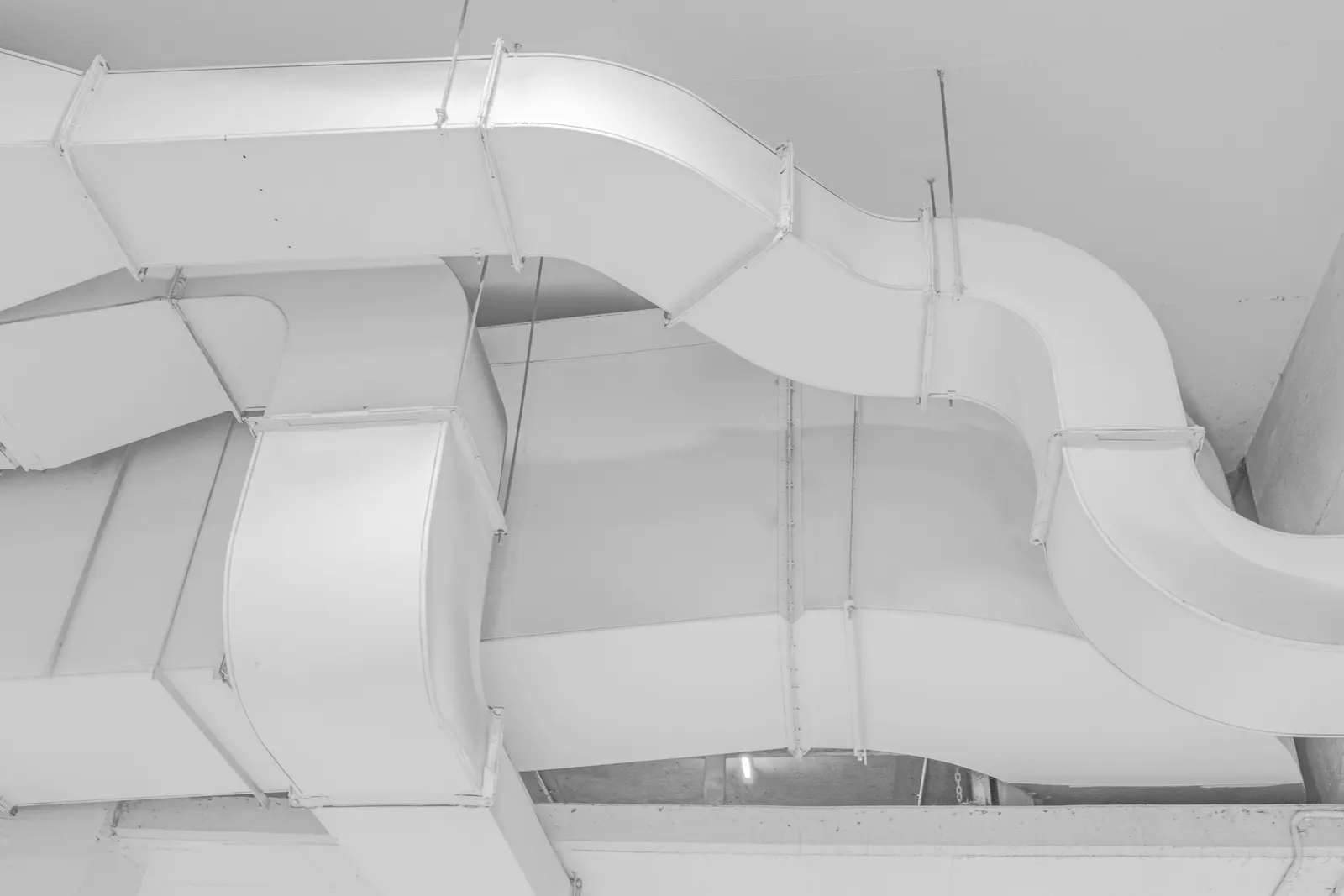 White sheet-metal ductwork running along a ceiling