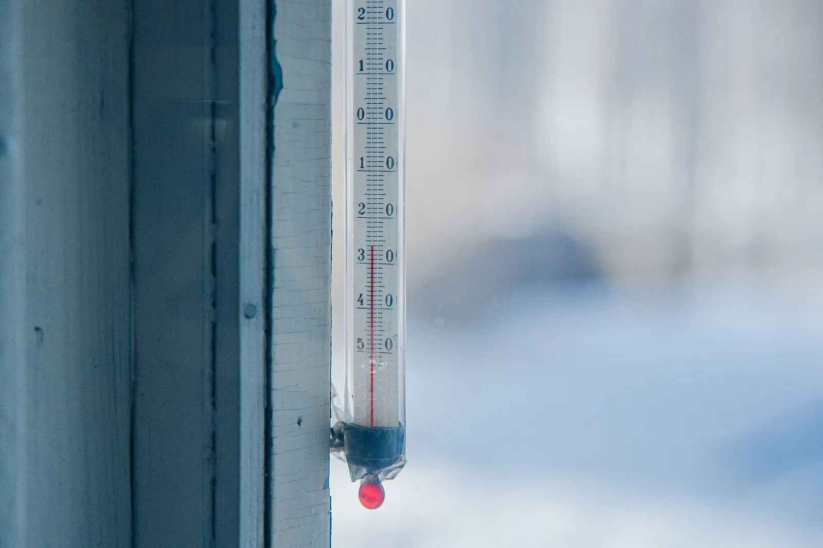 Window thermometer against a snowy winter background