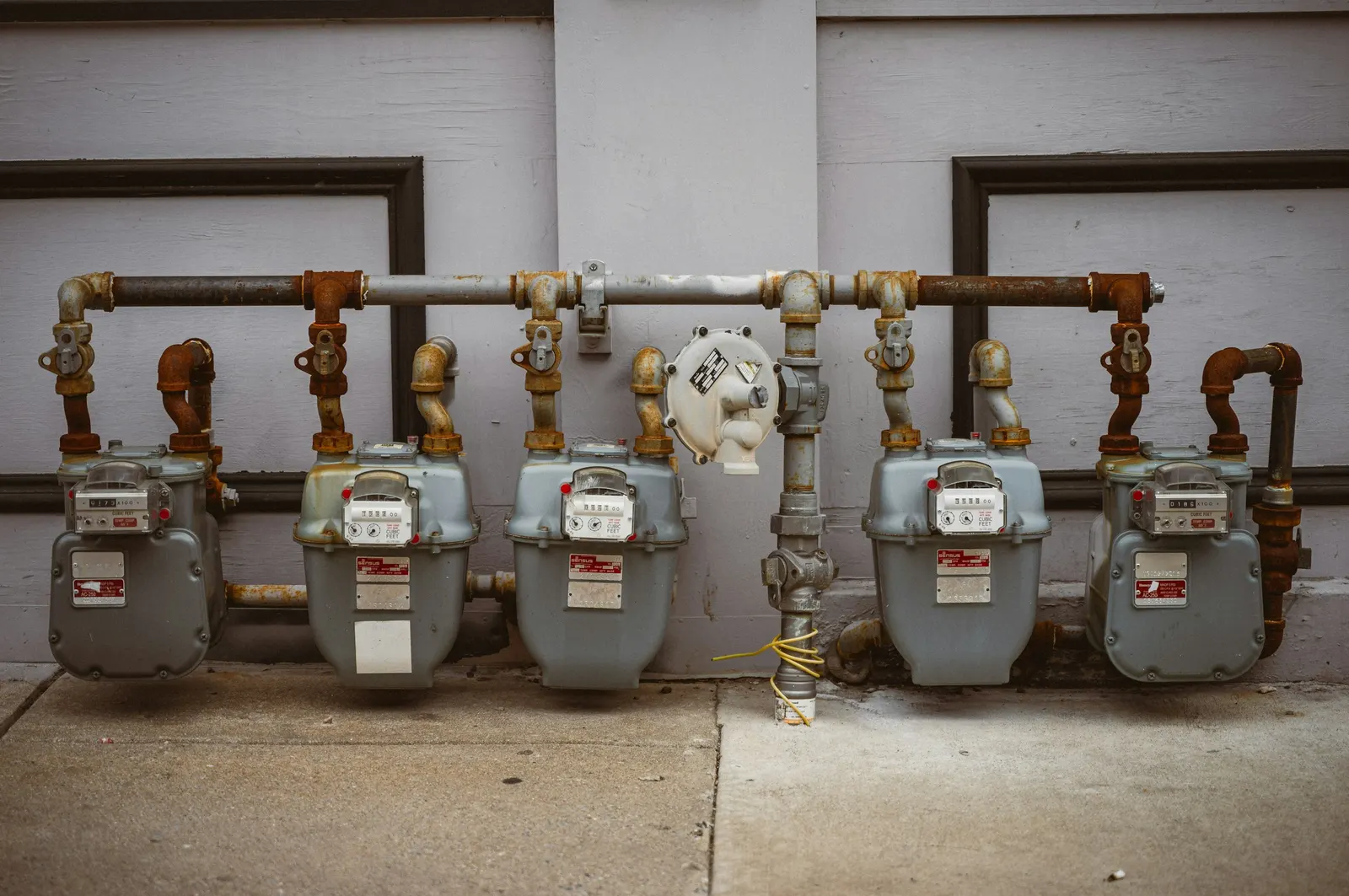 A row of residential natural gas meters on a building wall.
