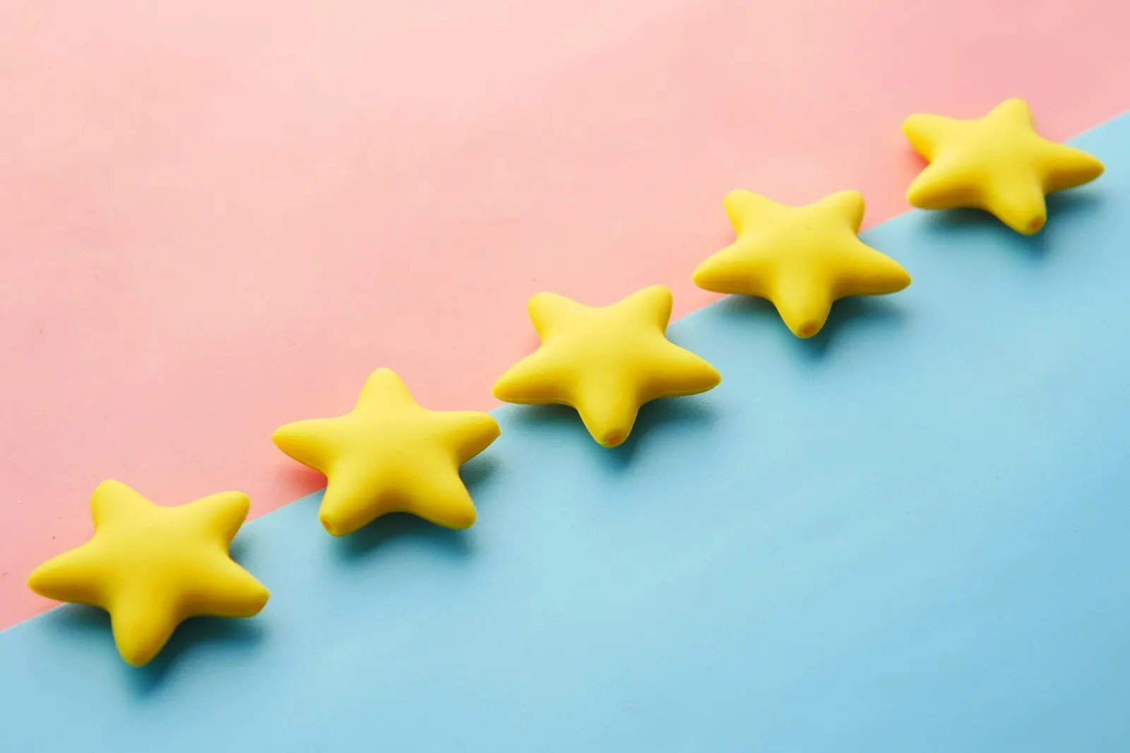 Five yellow stars in a diagonal row on a pink and blue background