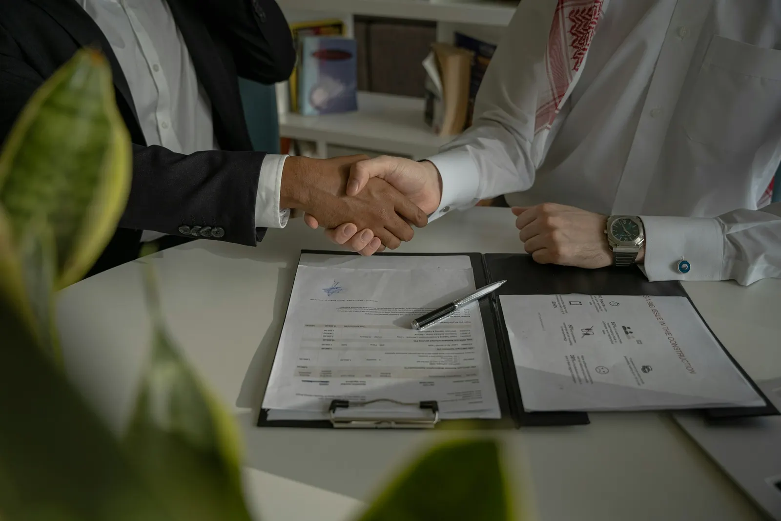 Handshake over a signed document folder on a desk